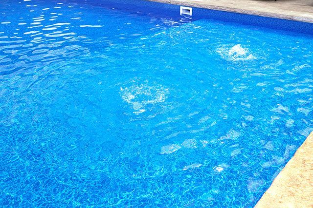 A swimming pool with blue water and bubbles coming out of it.
