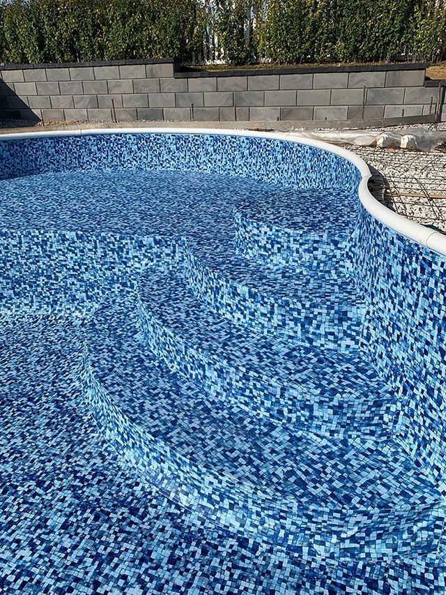 A blue swimming pool with a brick wall in the background.