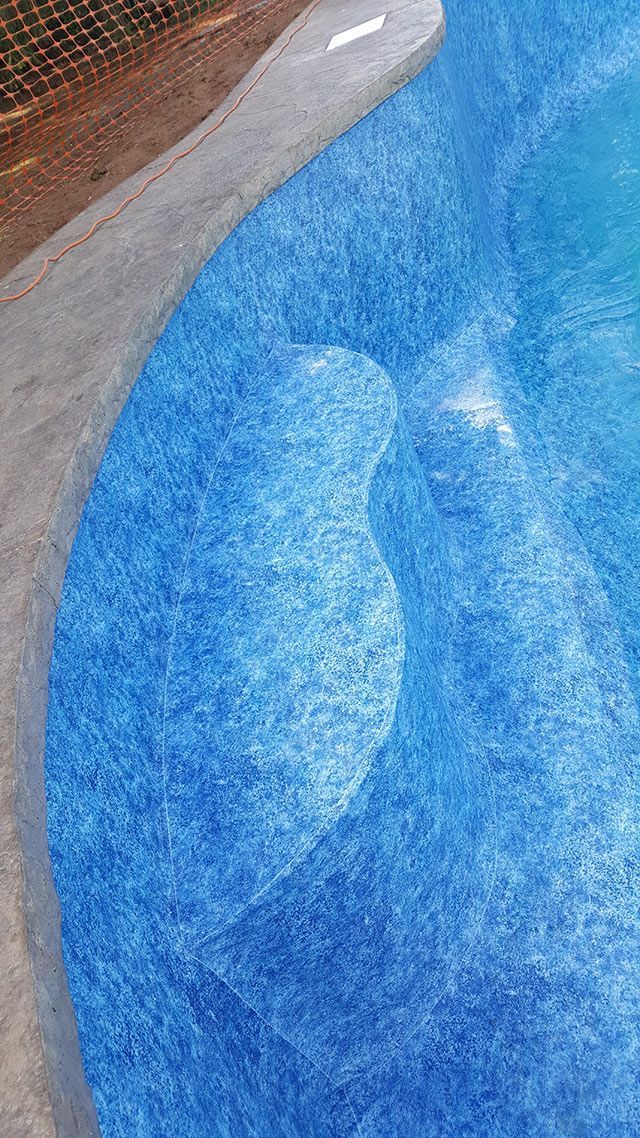 A close up of a blue swimming pool with steps leading into it.