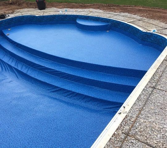 A blue swimming pool with stairs and a white border.