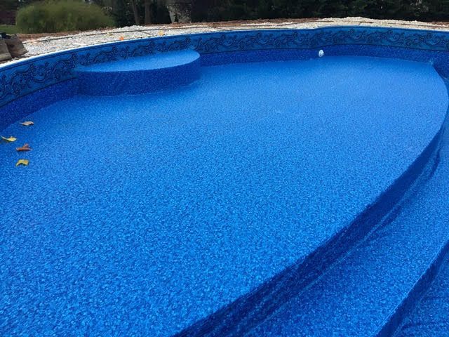 A large blue swimming pool with stairs leading to it.