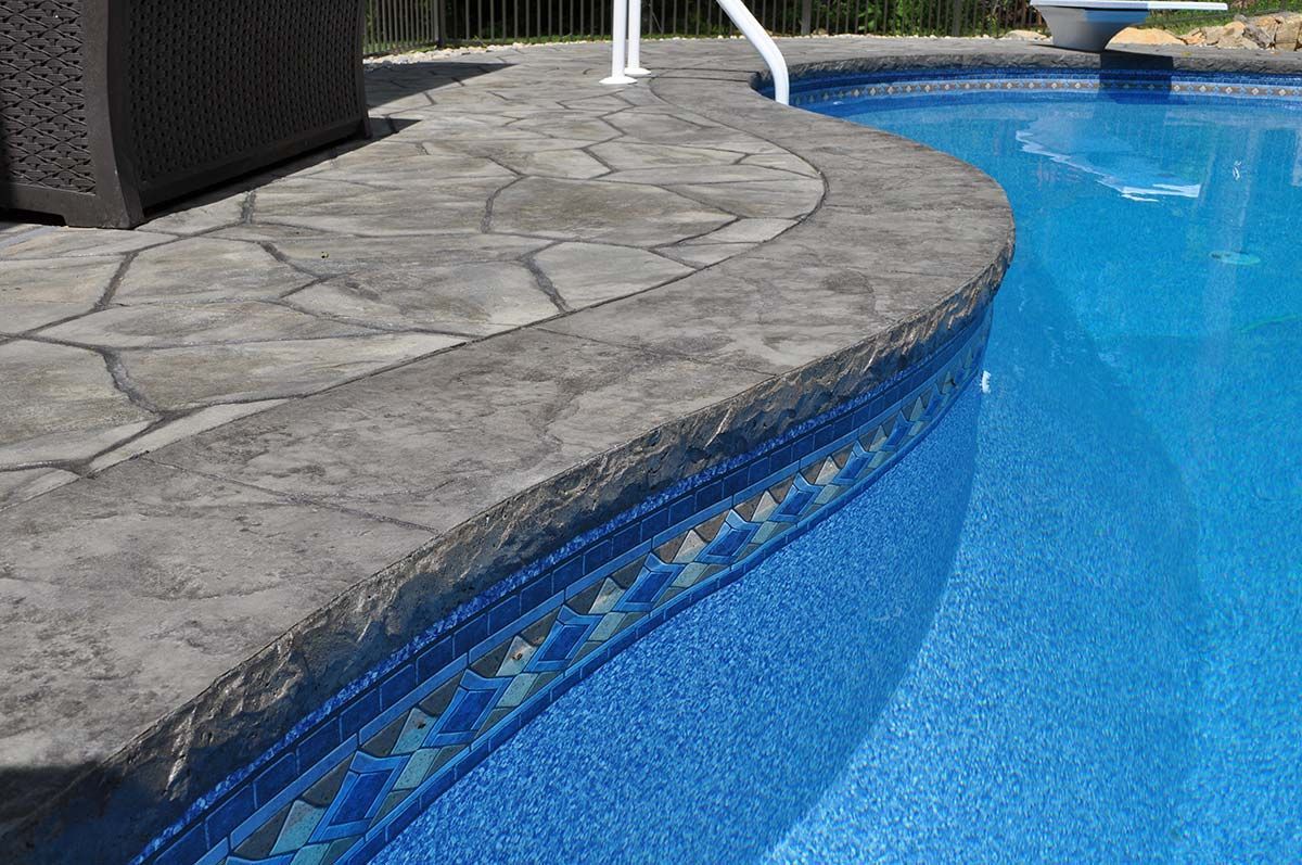 A swimming pool with a stone deck and steps leading into it.