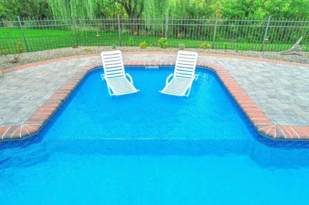 Two lounge chairs are floating in a swimming pool.