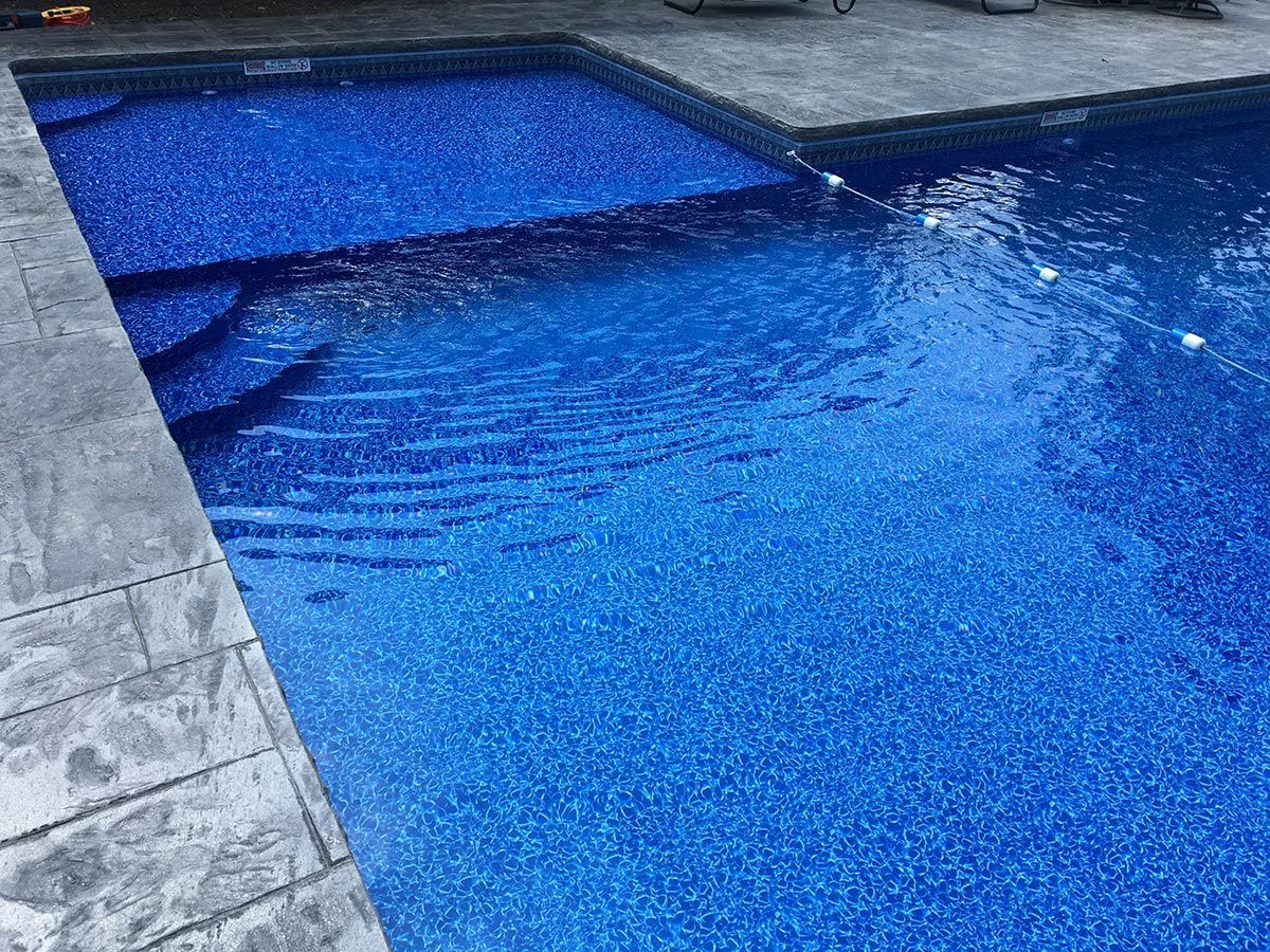 A large swimming pool filled with blue water and steps.