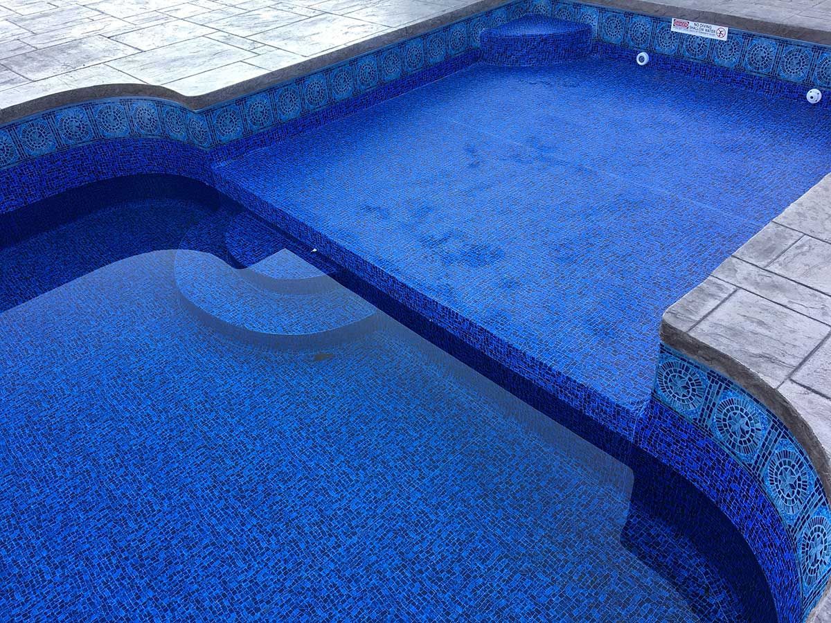 A large swimming pool with blue tiles and steps.