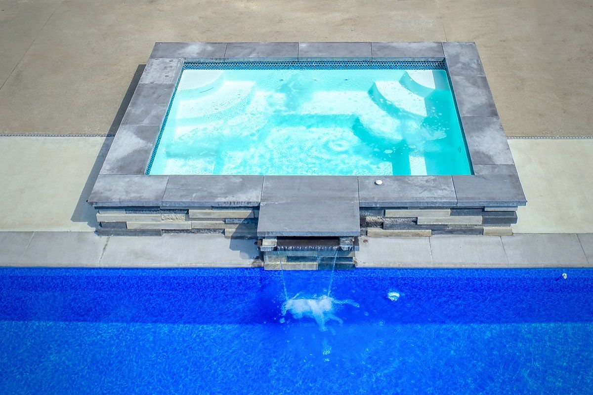 A swimming pool with a hot tub in the middle of it.