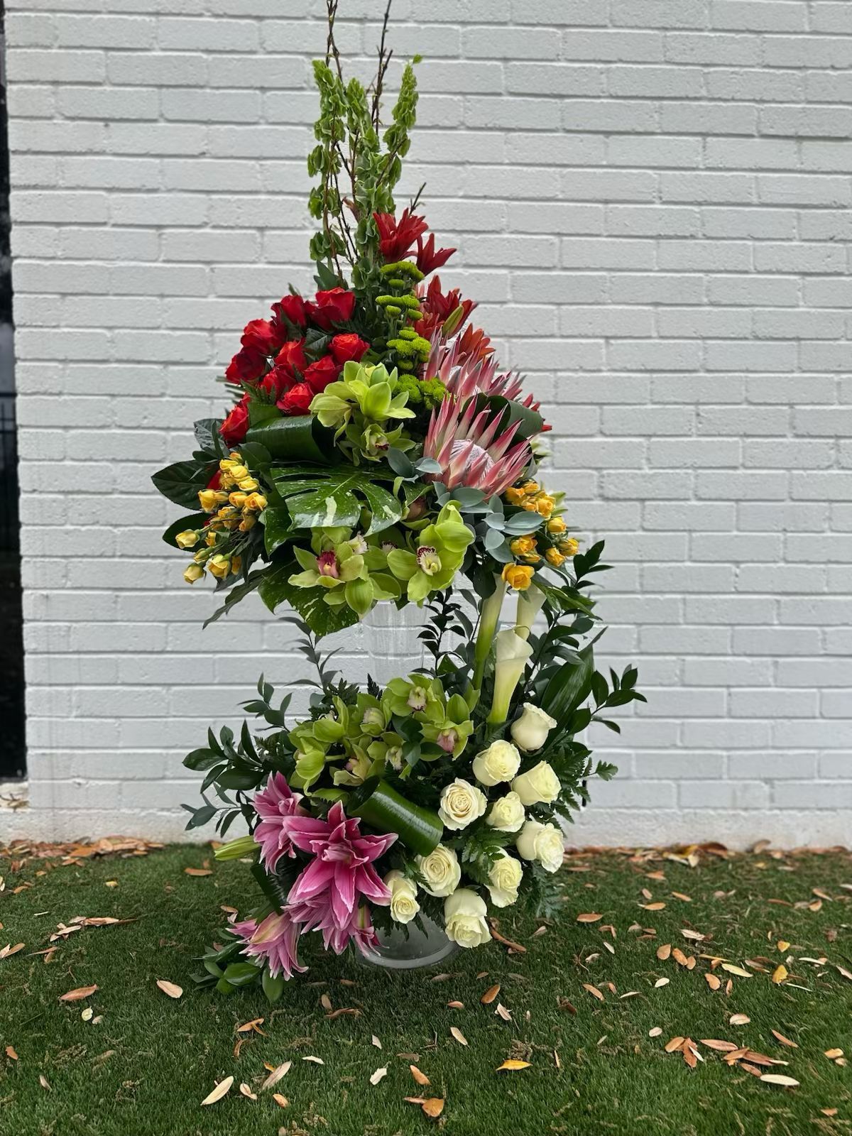 A large bouquet of flowers is sitting in front of a white brick wall.