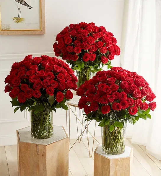 Three vases filled with red roses are sitting on wooden blocks