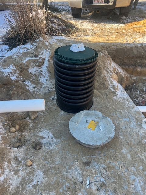 A septic tank is sitting on the ground next to a concrete block.