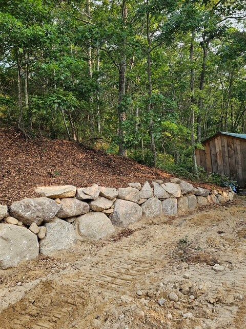 A stone wall is being built in the middle of a forest.