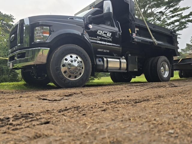 A dump truck is parked on the side of a dirt road.