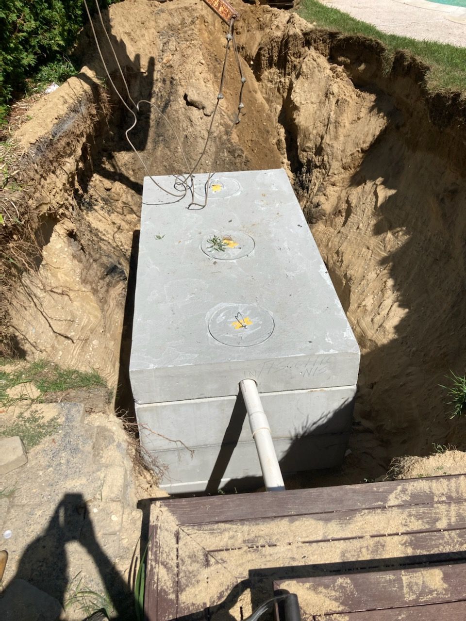 A large concrete tank is being installed in a hole in the ground.