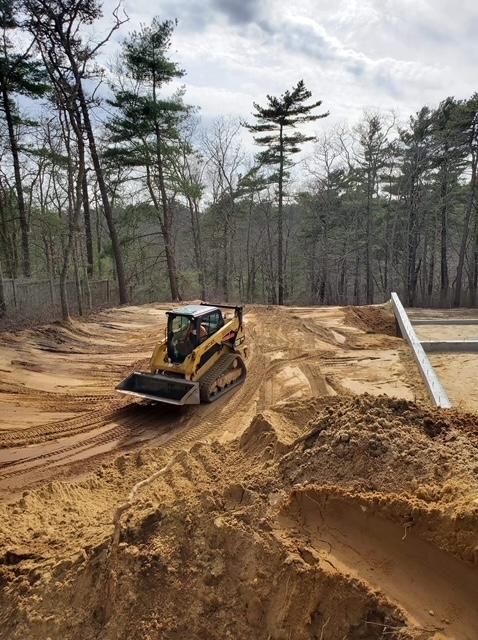 A bulldozer is driving down a dirt road in the woods.