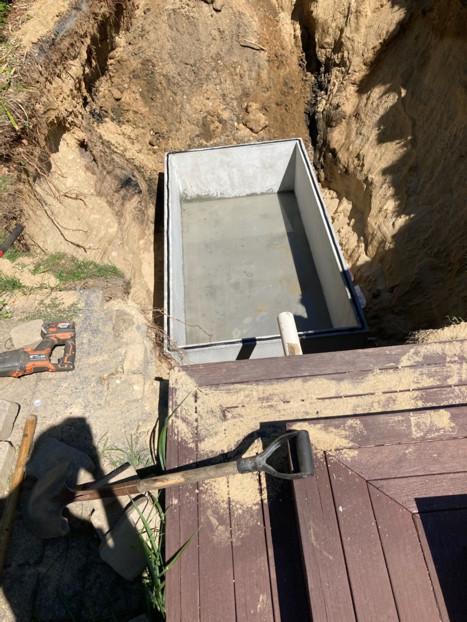 A wheelbarrow is sitting in the dirt next to a wooden deck.