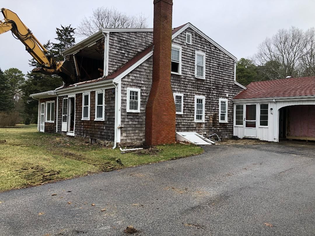 A large house is being demolished by a bulldozer.