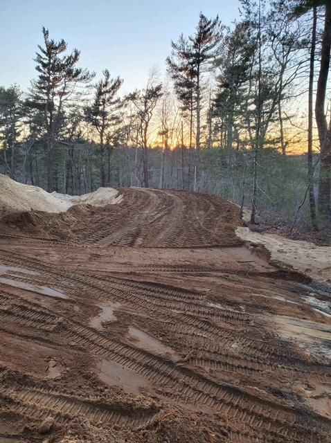 A large pile of dirt is sitting in the middle of a forest.