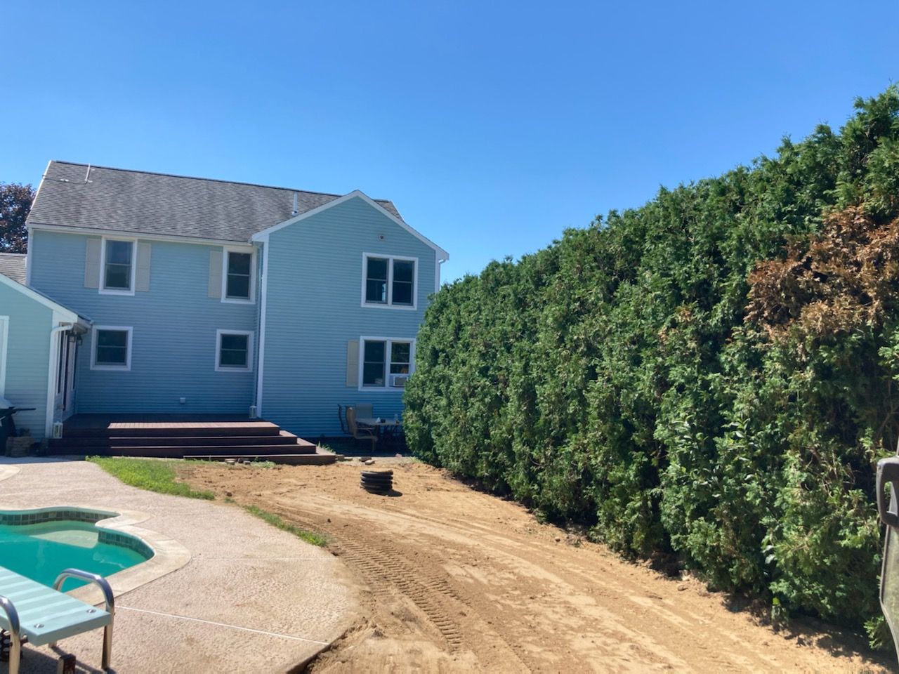A house with a pool and a hedge in front of it.