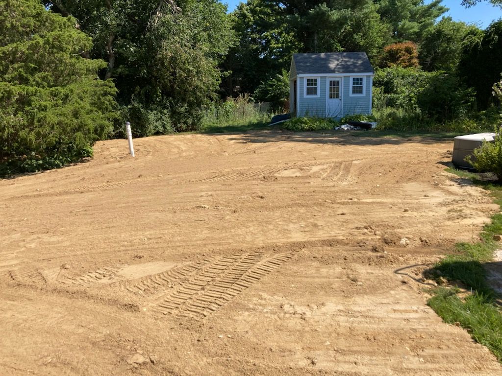 A small white house is sitting in the middle of a dirt field.