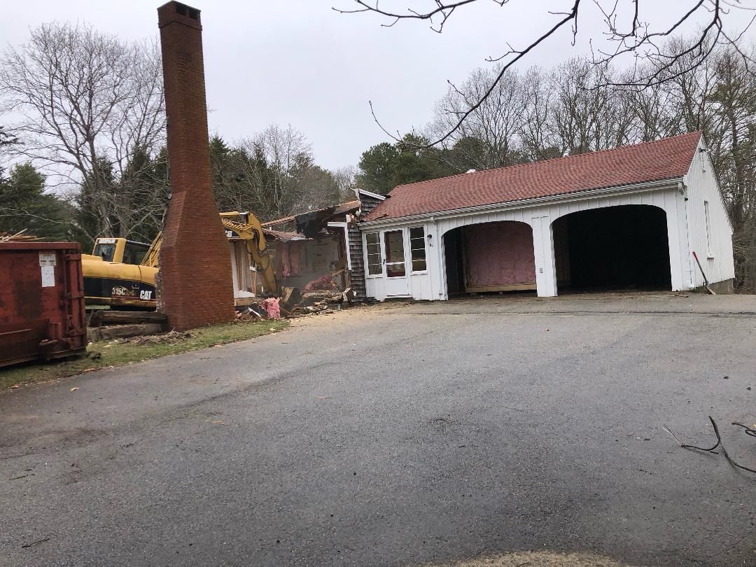 A white house with a red roof is being demolished.