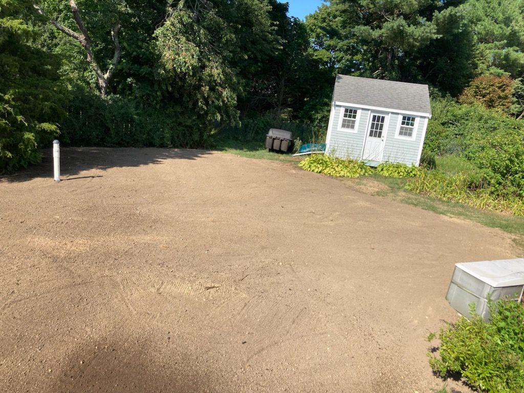 A small white house is sitting in the middle of a dirt road.
