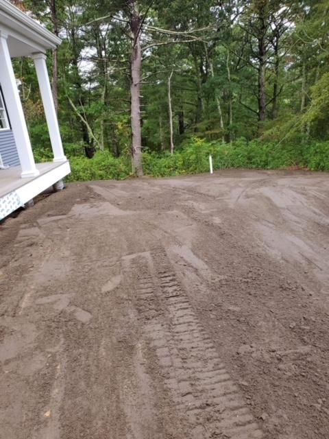 A dirt road leading to a house with trees in the background