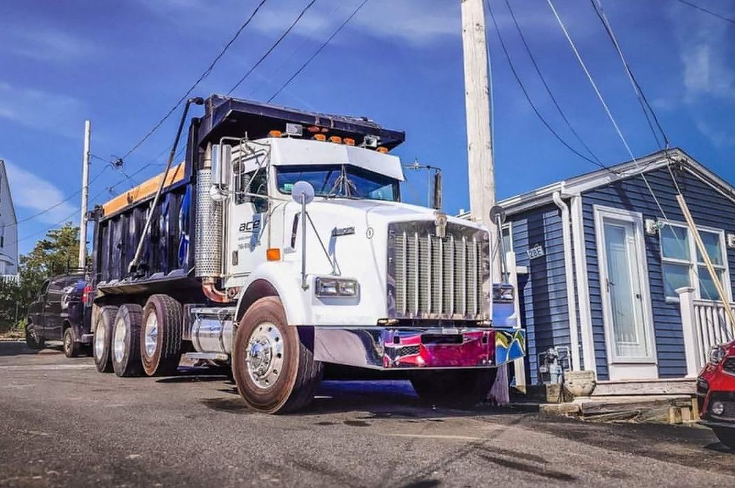 A dump truck is parked in front of a blue house.