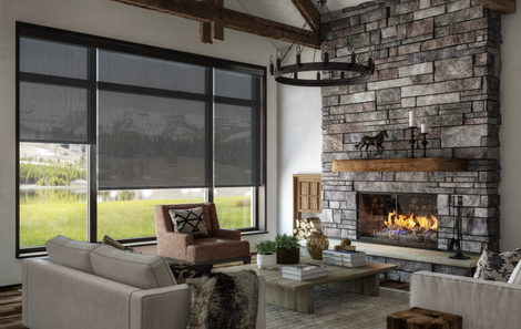 Living room with stone fireplace, large windows with shades, and view of a lake.