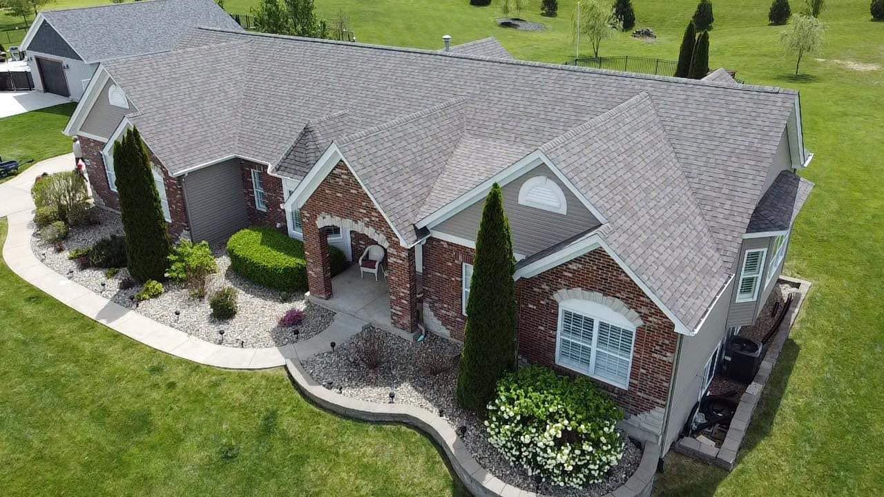 An aerial view of a large brick house with a gray roof.