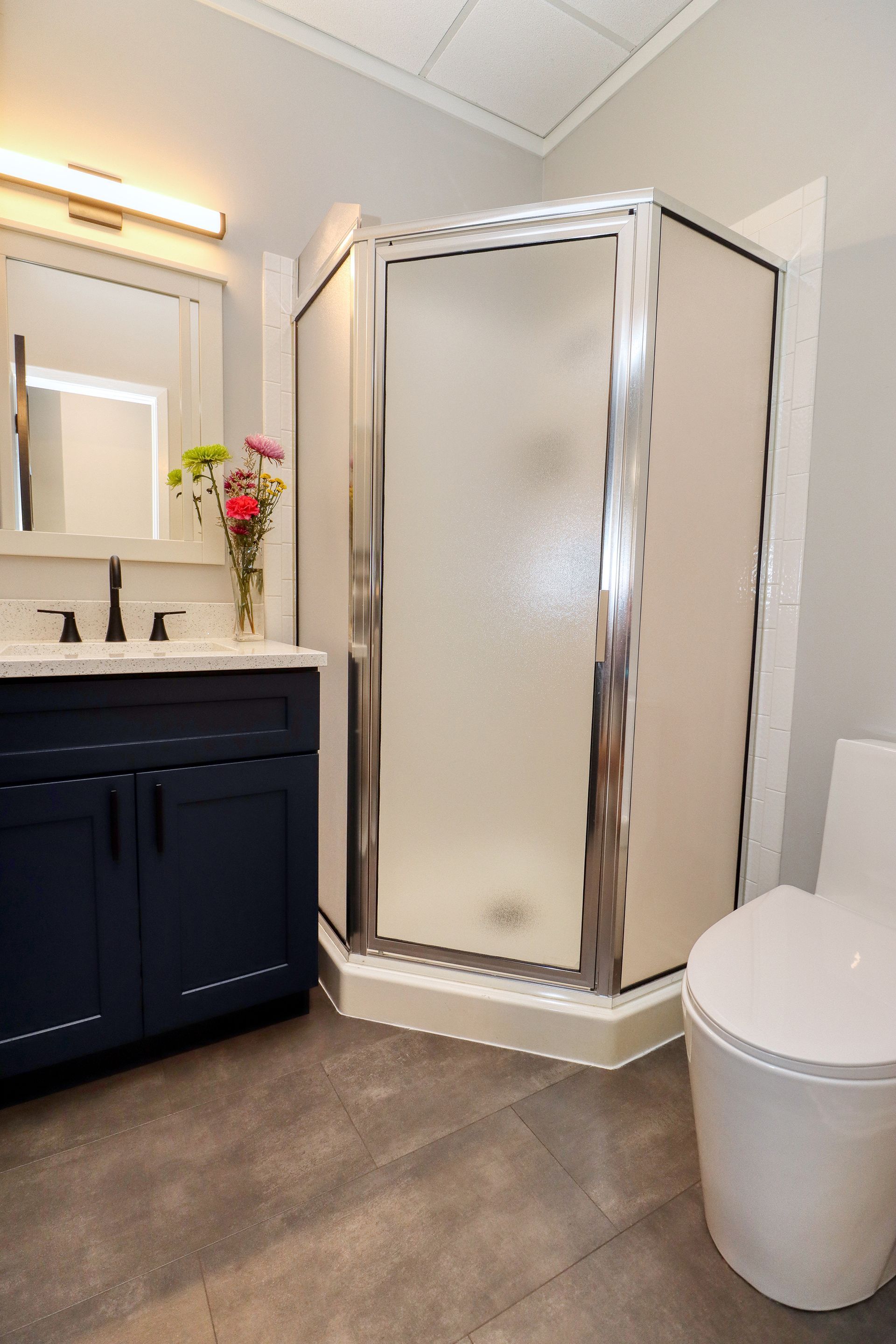 A bathroom with a toilet , sink , shower and mirror.