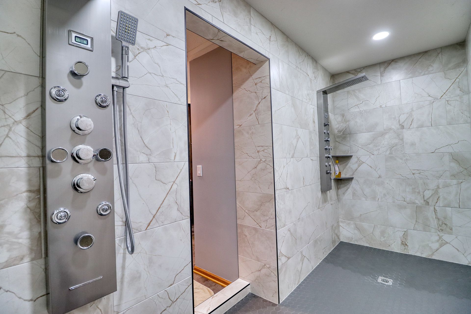 A bathroom with a walk in shower and a stainless steel shower head.