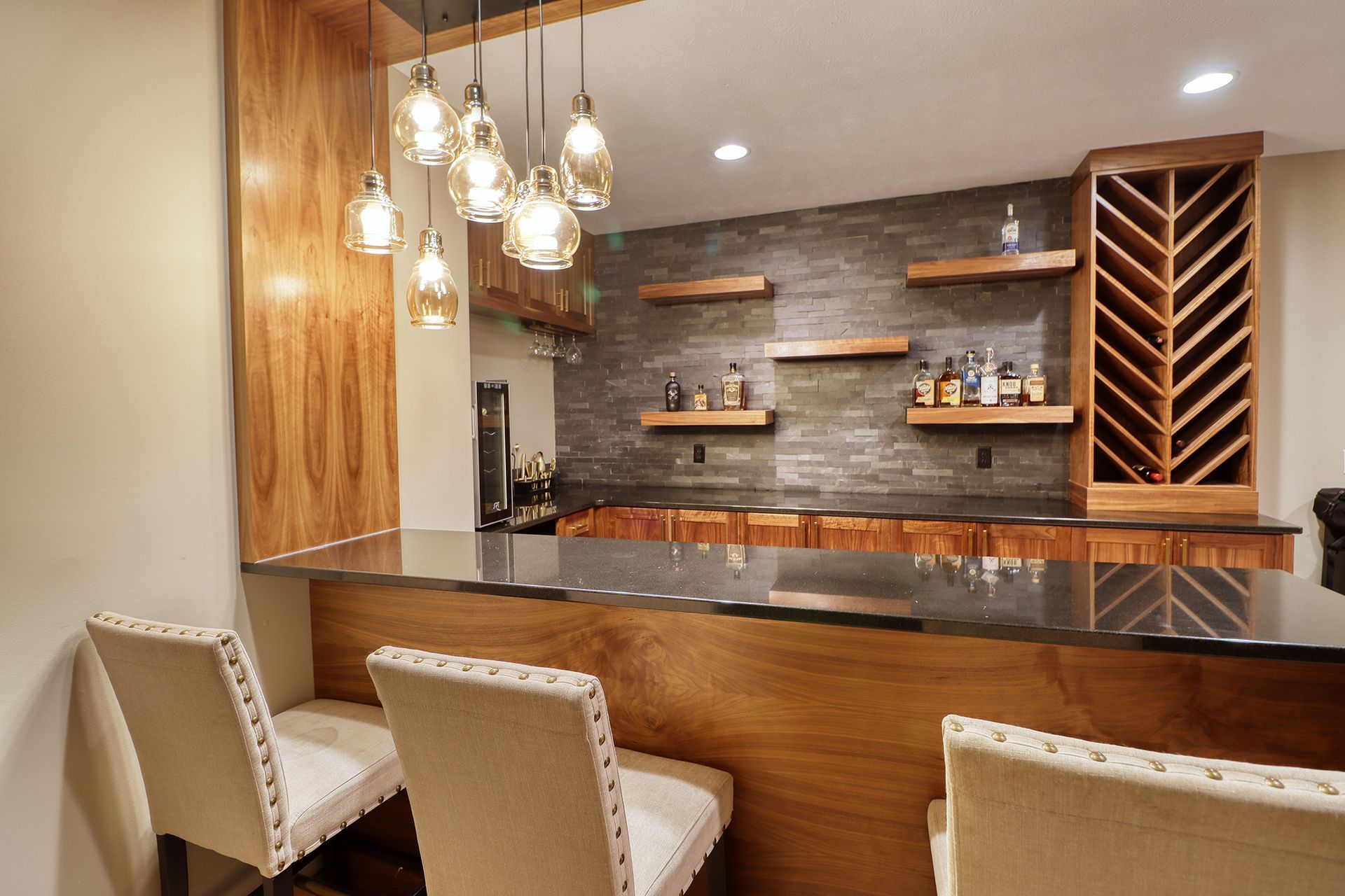A kitchen with a bar and chairs and a wine rack.