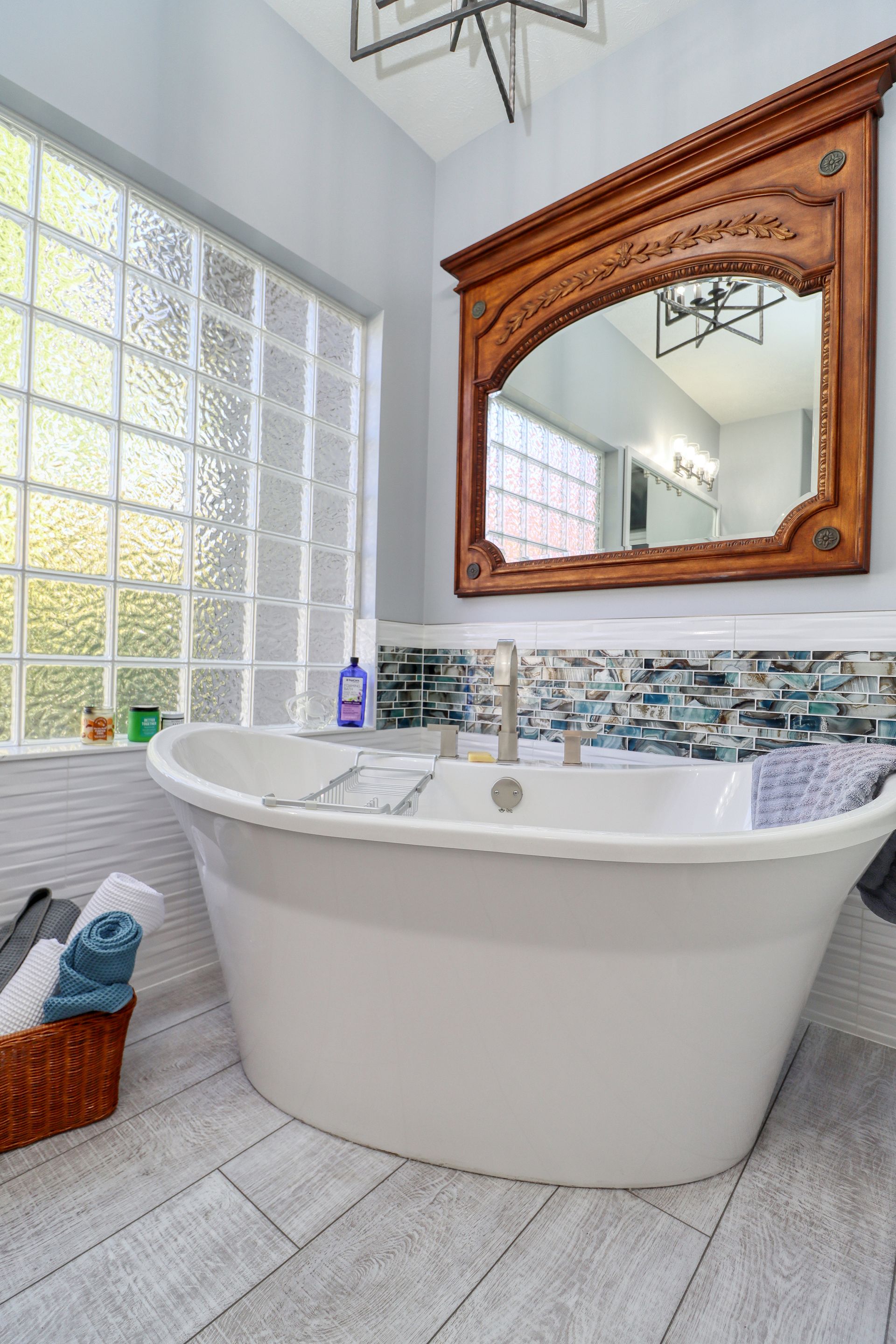 A bathroom with a tub , mirror and window.