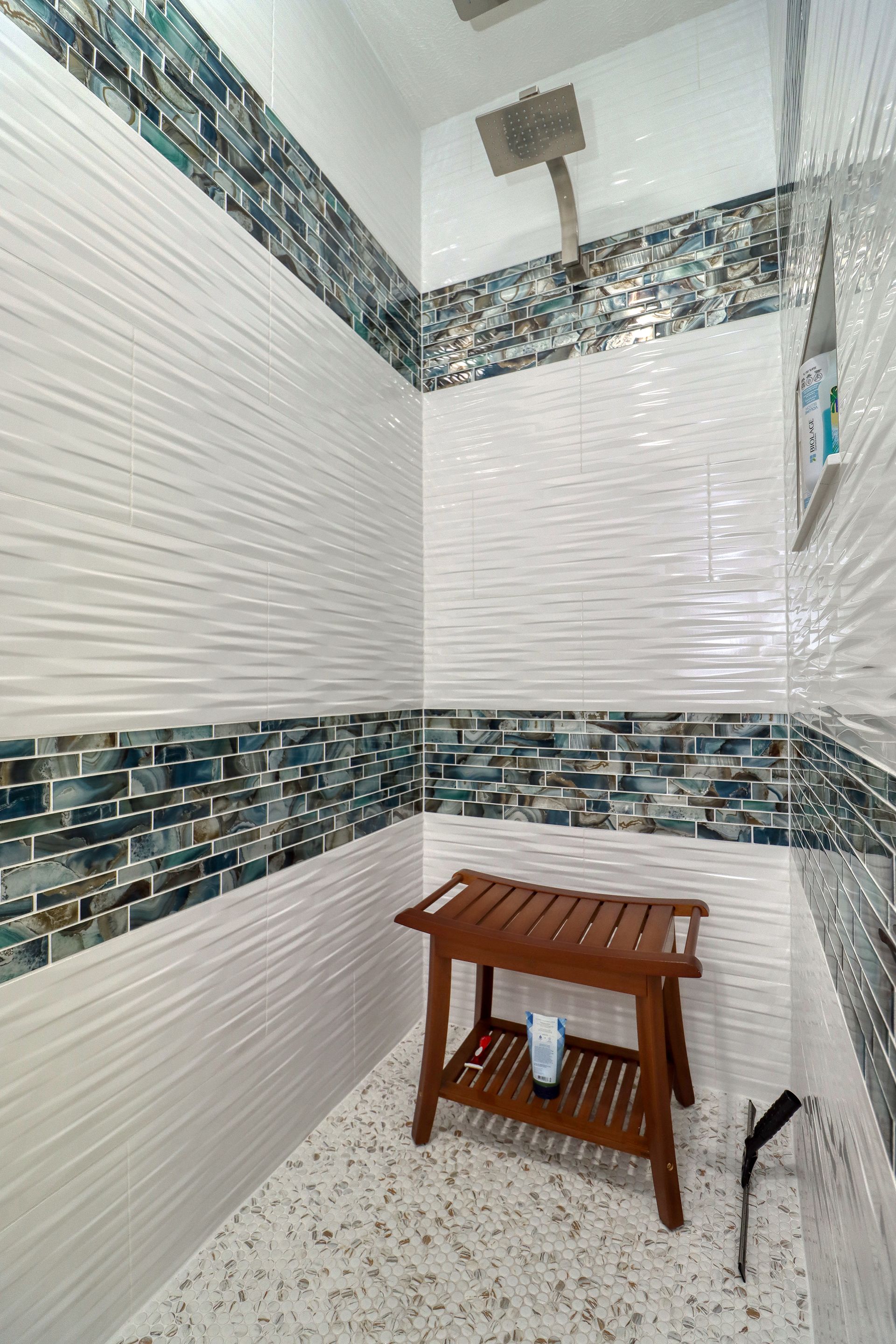 A bathroom with a wooden bench and a shower head.