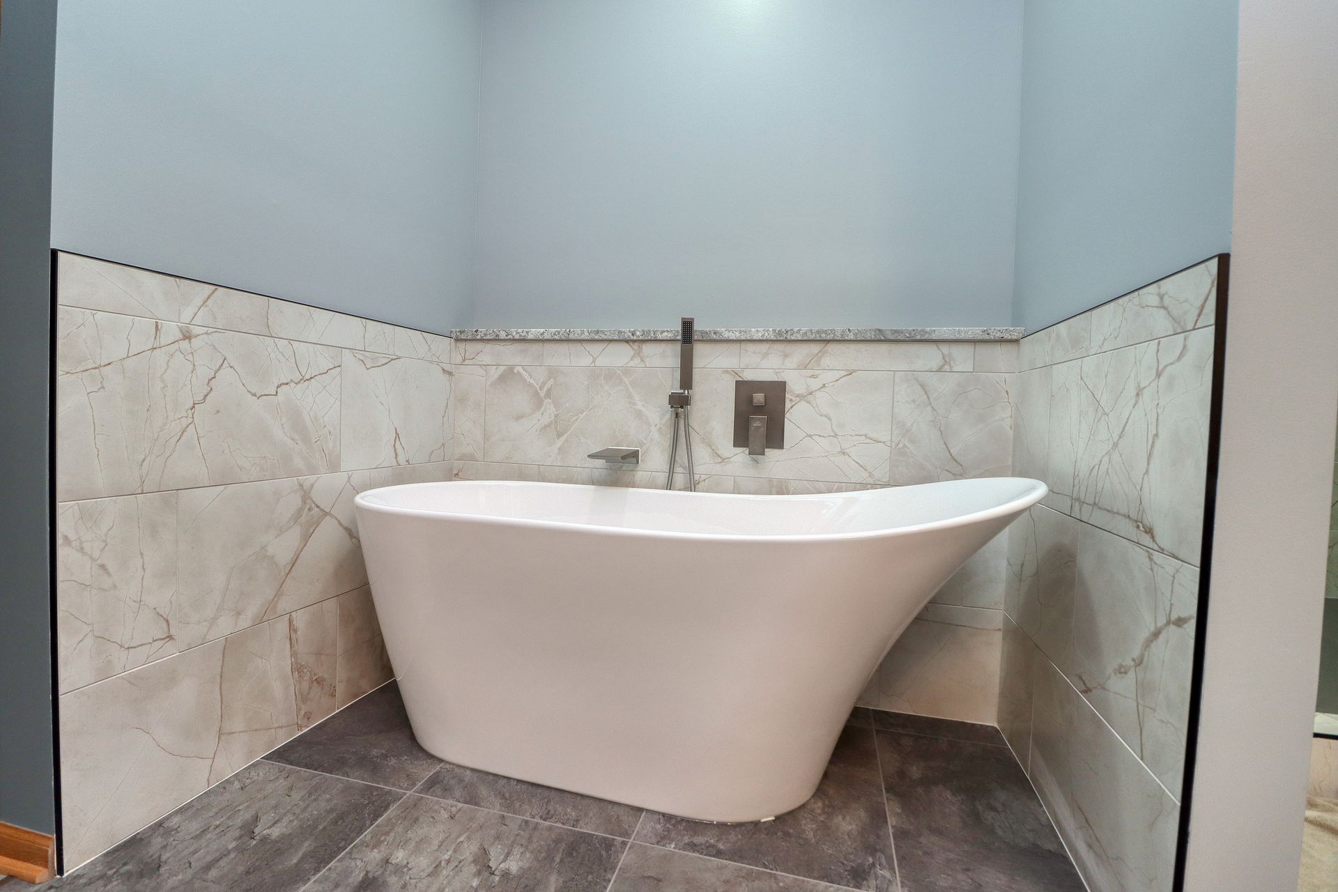 A white bathtub is sitting in a bathroom next to a wall.