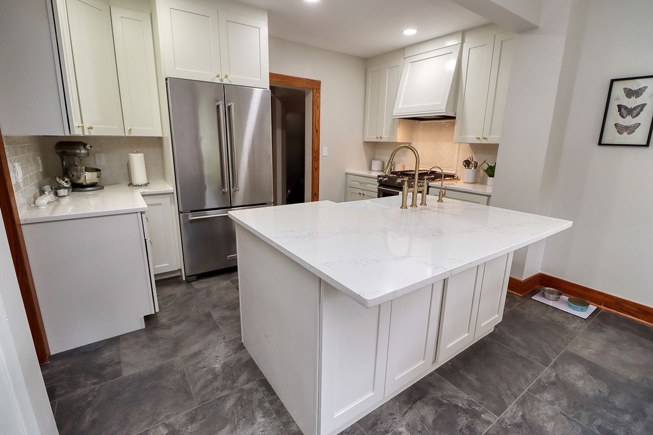 A kitchen with white cabinets , stainless steel appliances , and a large island.