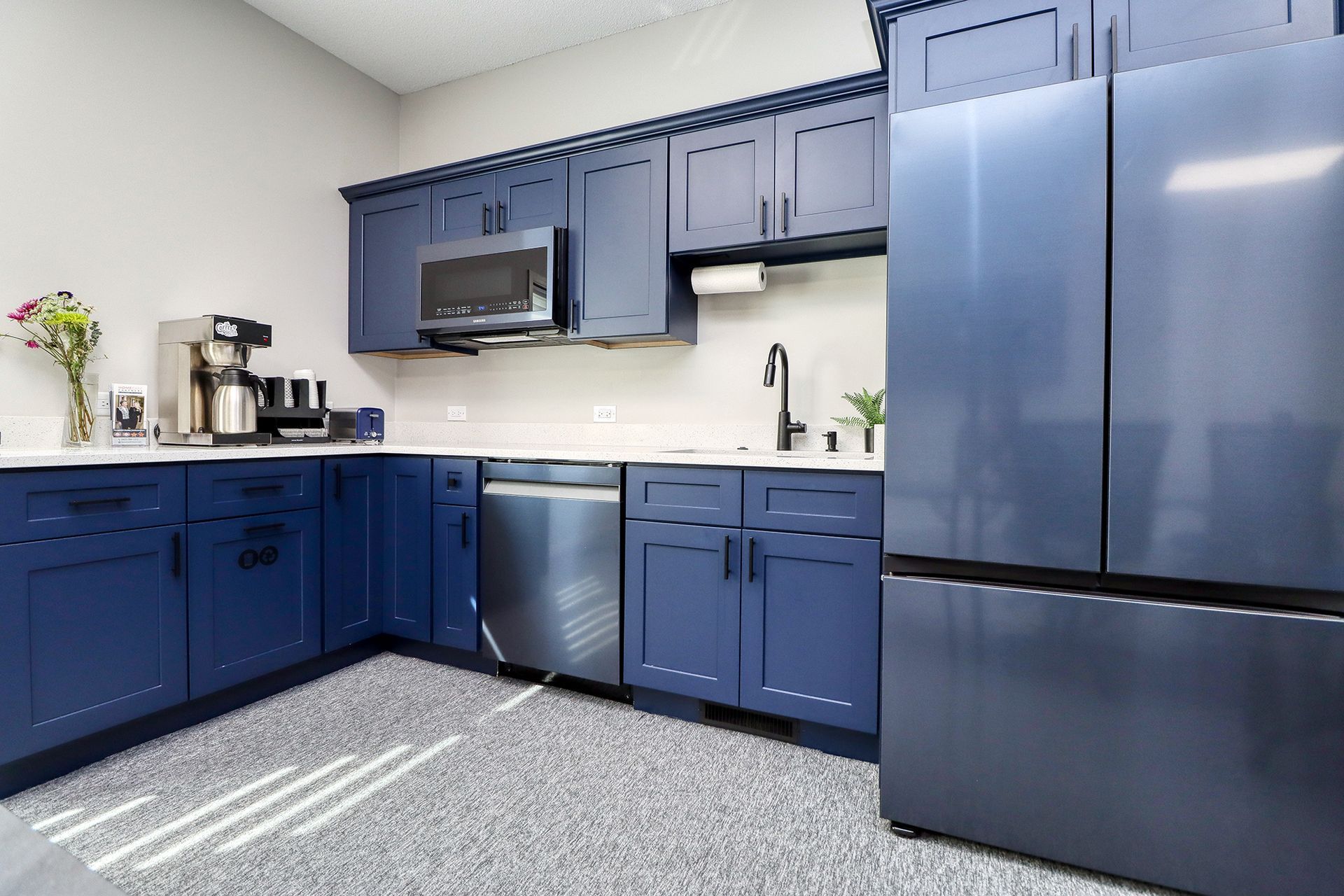 A kitchen with blue cabinets and stainless steel appliances.