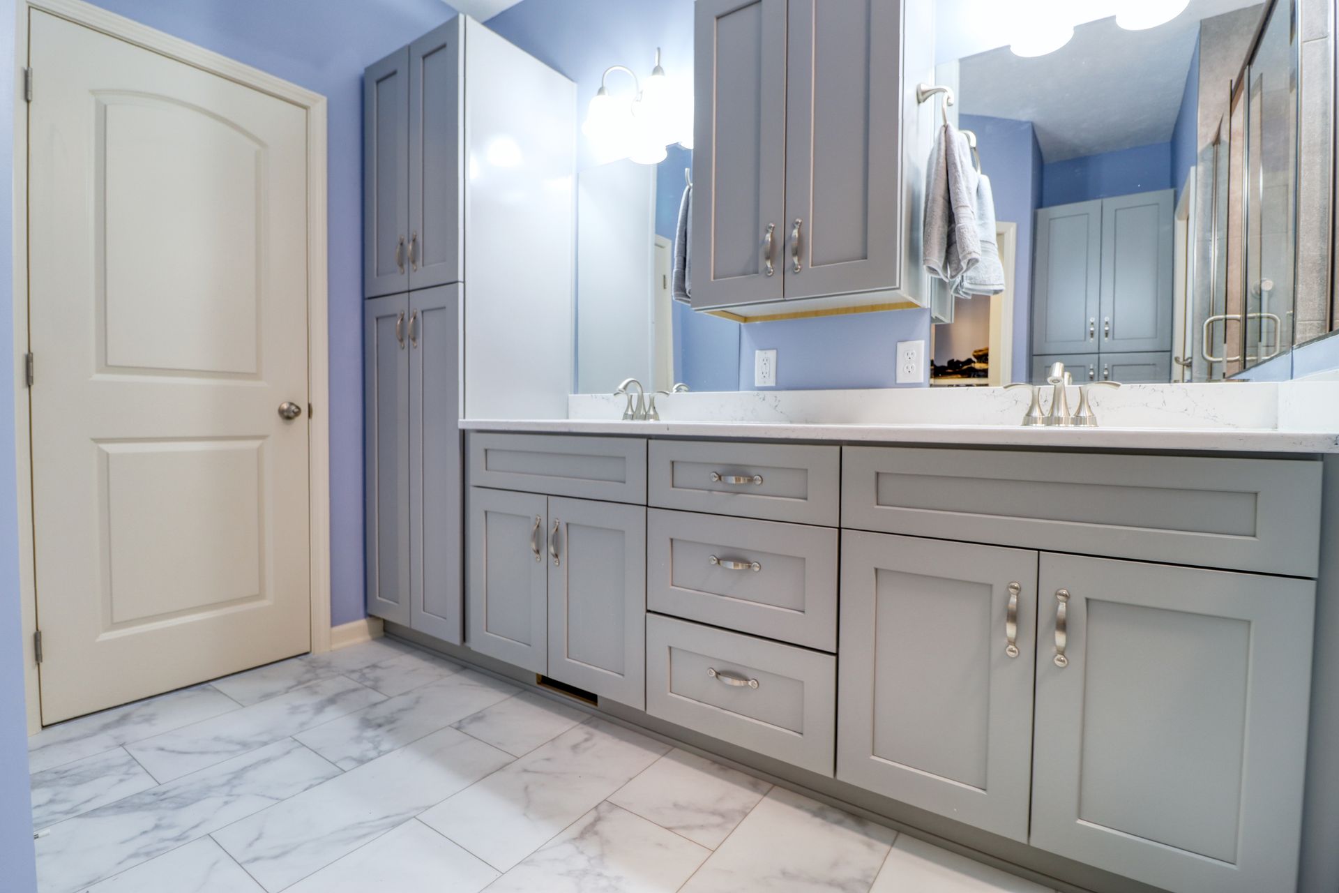 A bathroom with gray cabinets , a sink and a mirror.