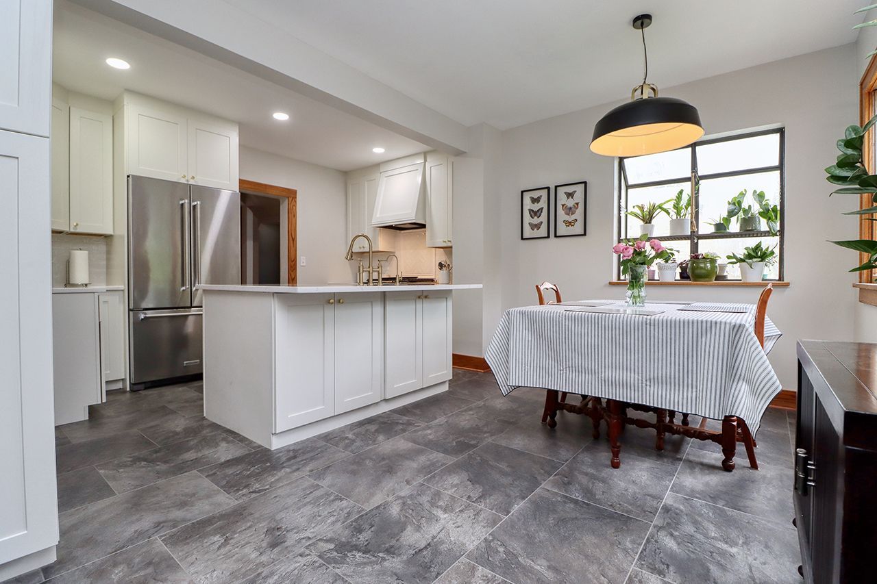 A kitchen with a table and chairs in it and a stainless steel refrigerator.