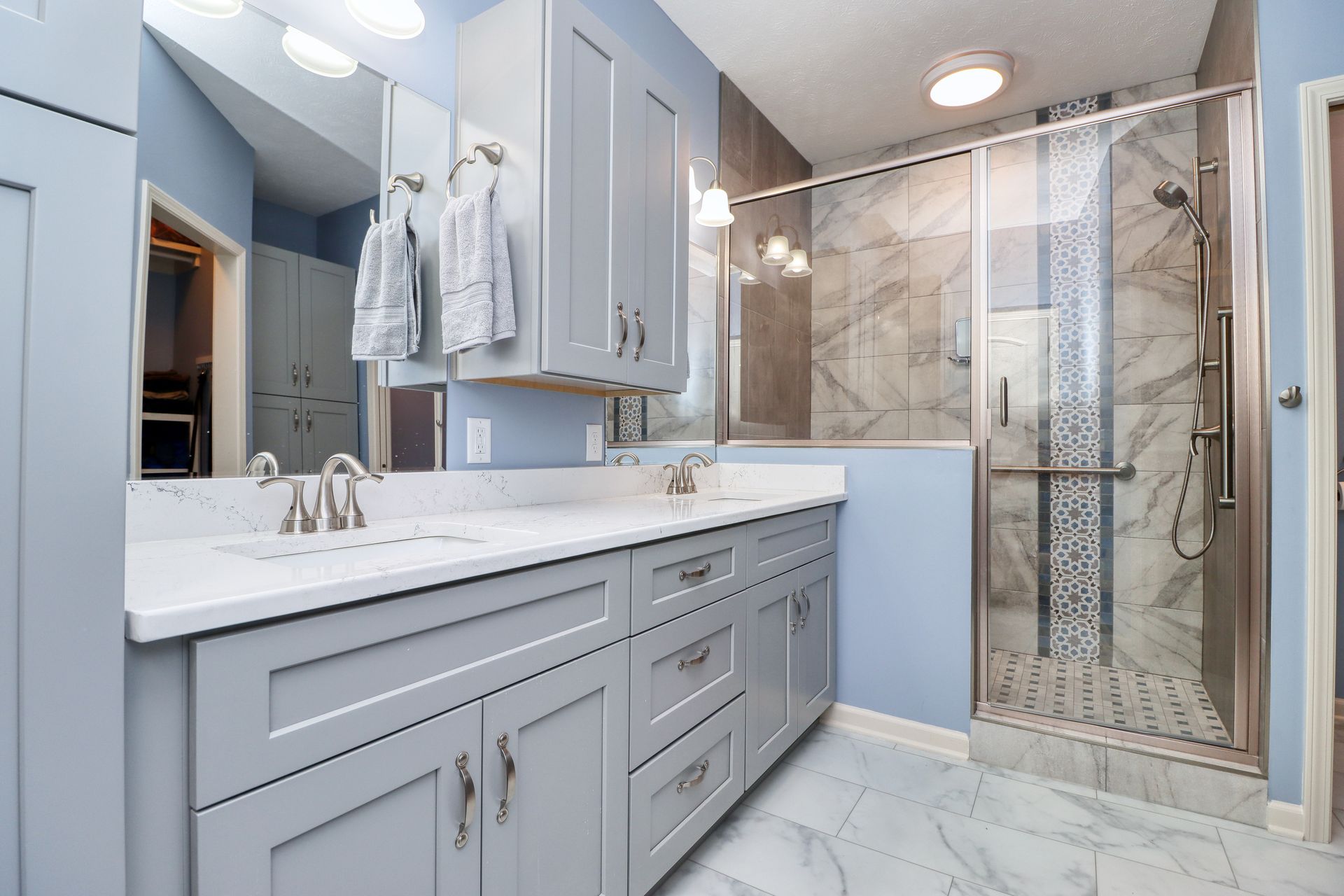 A bathroom with a sink , mirror , and walk in shower.