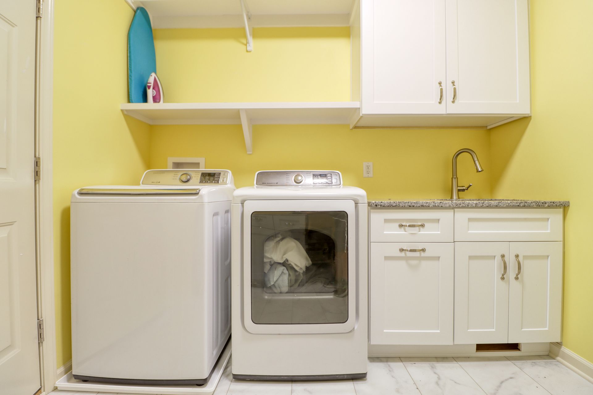 A laundry room with a washer and dryer and yellow walls.
