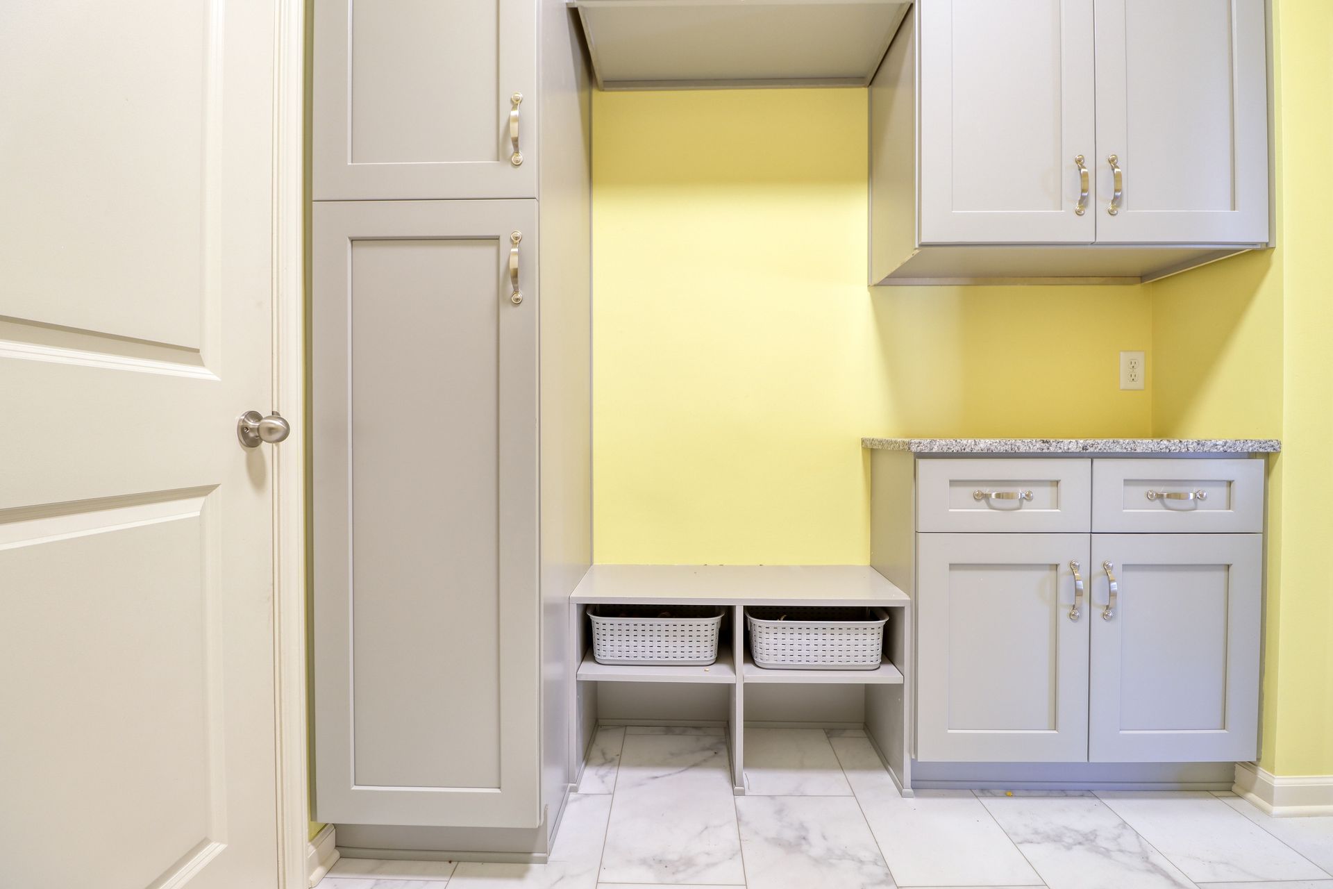 A laundry room with gray cabinets and yellow walls.