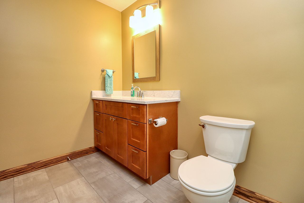 A bathroom with a toilet , sink and mirror.
