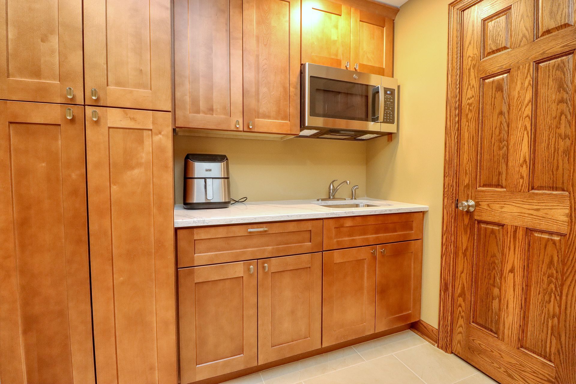 A kitchen with wooden cabinets , a sink , and a microwave.