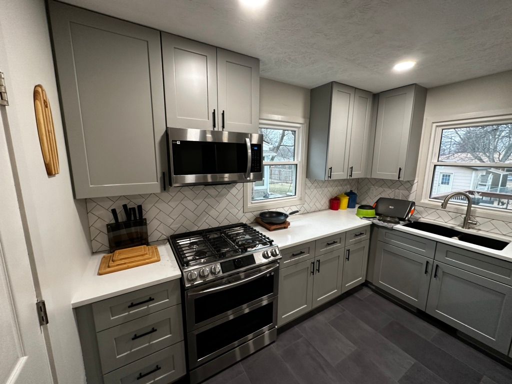 A kitchen with gray cabinets and stainless steel appliances
