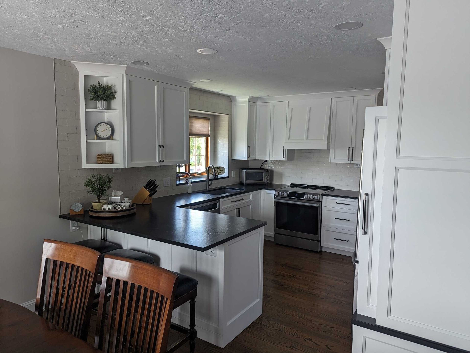 A kitchen with white cabinets and a black counter top.