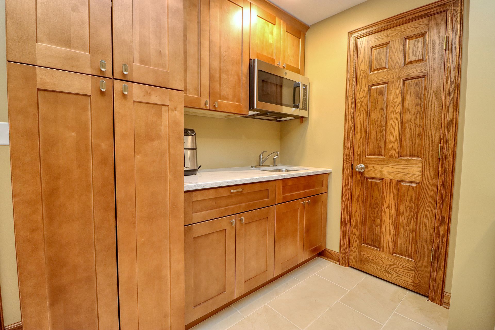 A kitchen with wooden cabinets and a stainless steel microwave