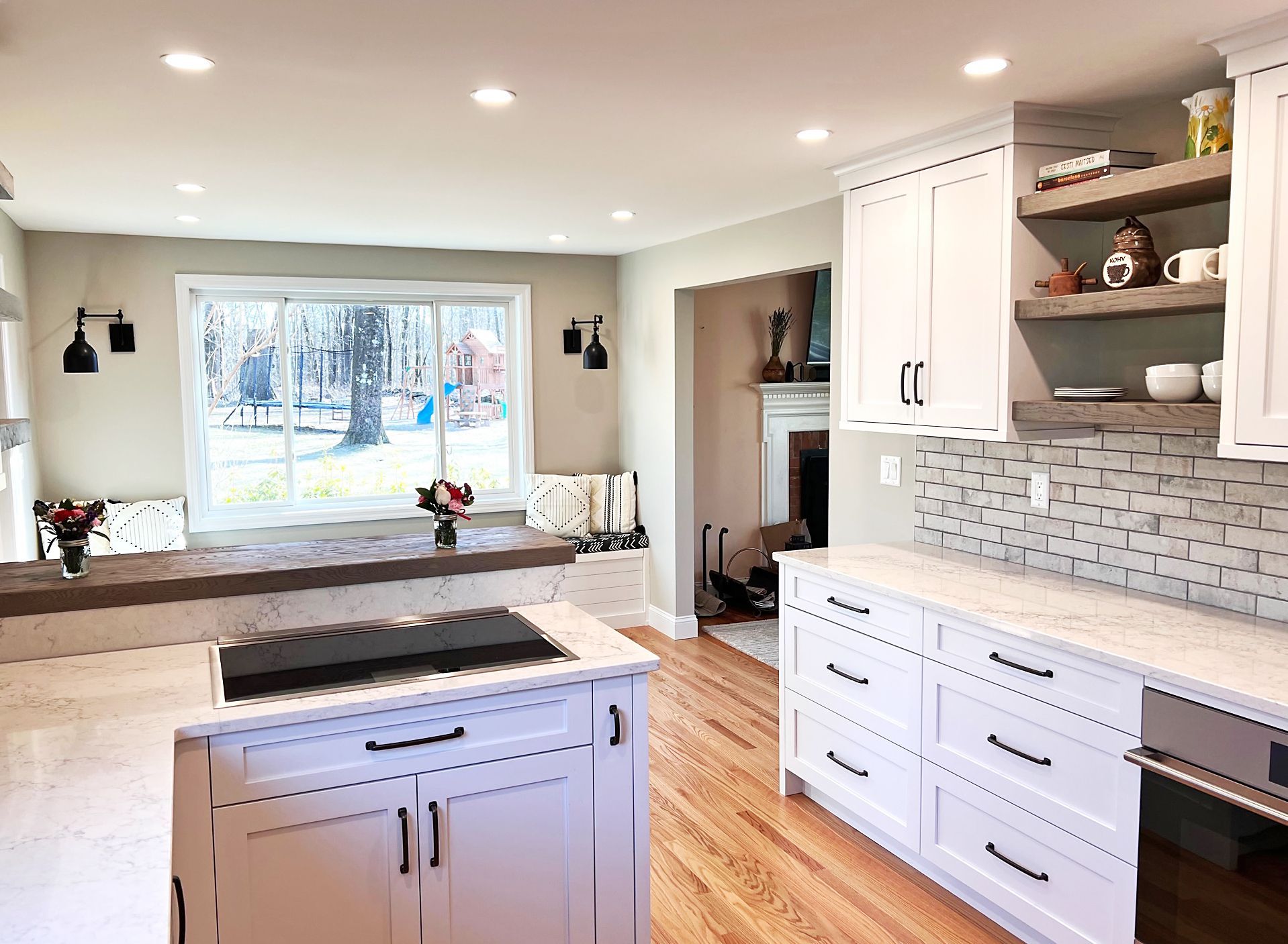 a kitchen with white cabinets, hardwood floors, a stove and a window