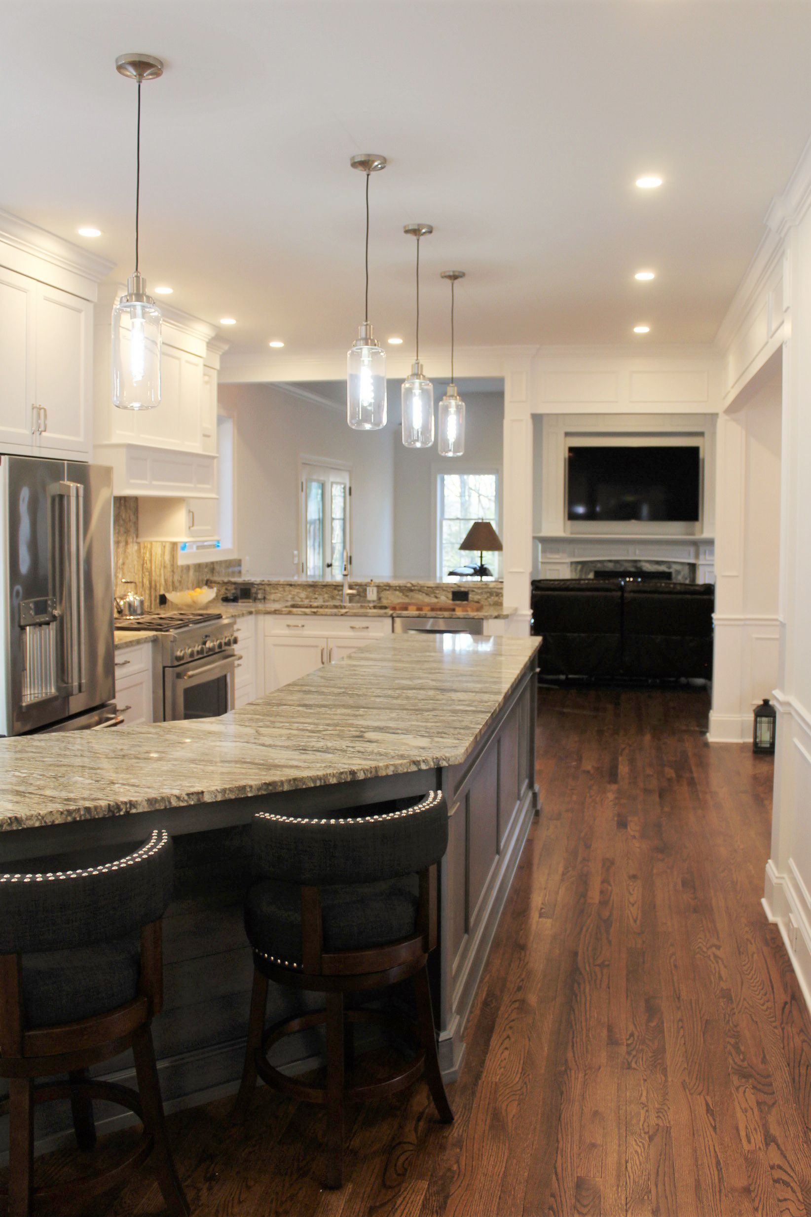 a kitchen with a large island, stools and a refrigerator