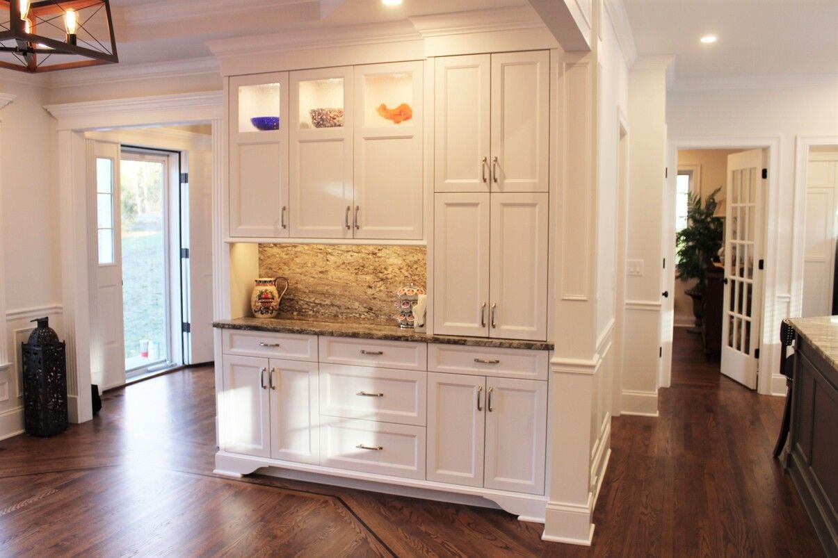 a kitchen with white cabinets, granite counter tops and hardwood floors