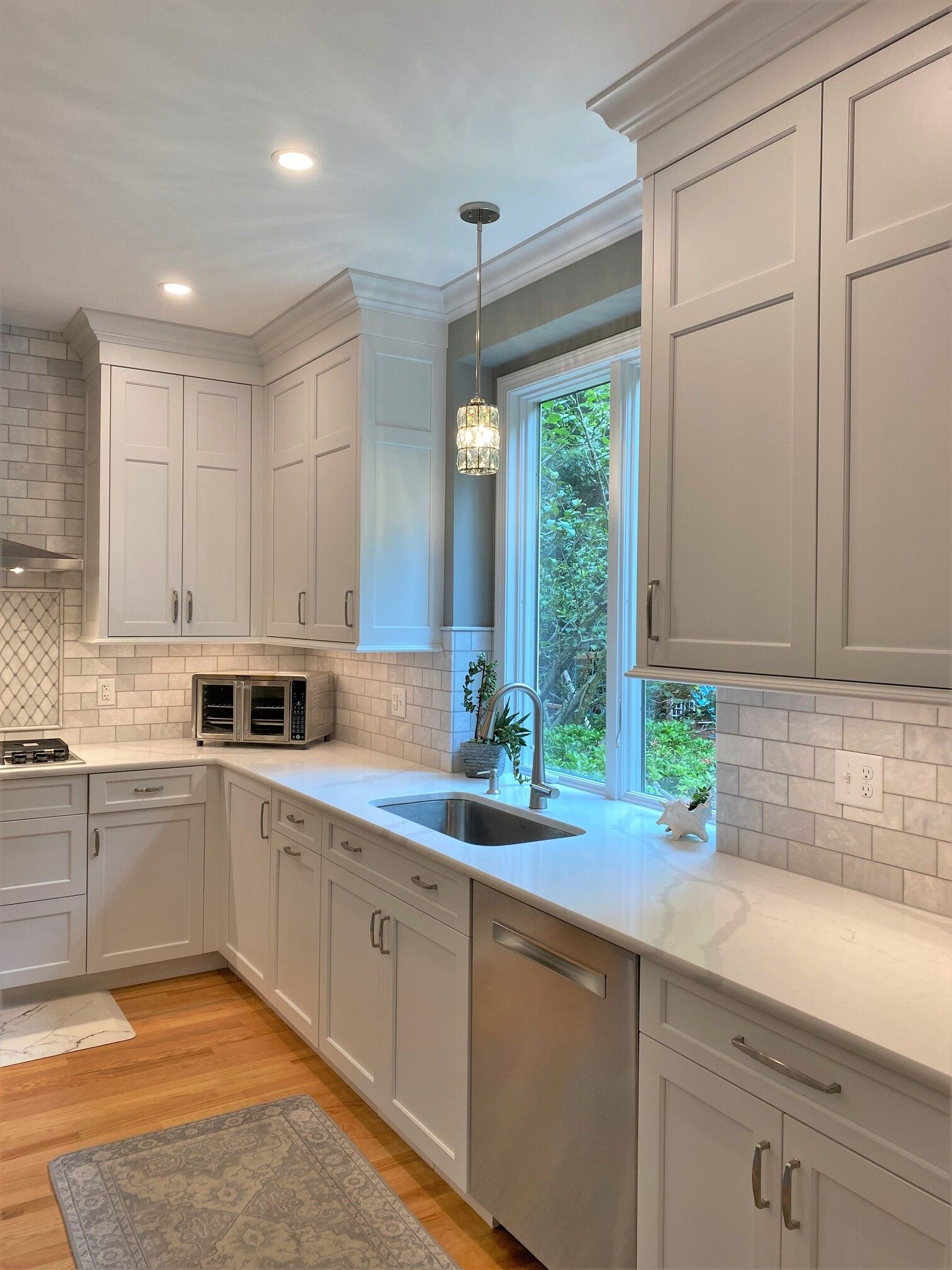 a kitchen with white cabinets, a sink, and a window